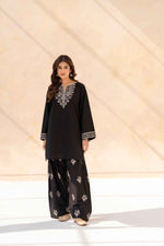 Full-length view of model wearing Cloothy Aylin black lawn suit with intricate embroidery.
